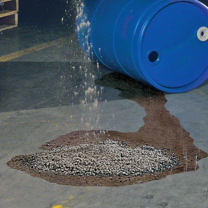 Granular mineral sponge poured onto a fresh spill to absorb oil and chemicals on a concrete floor